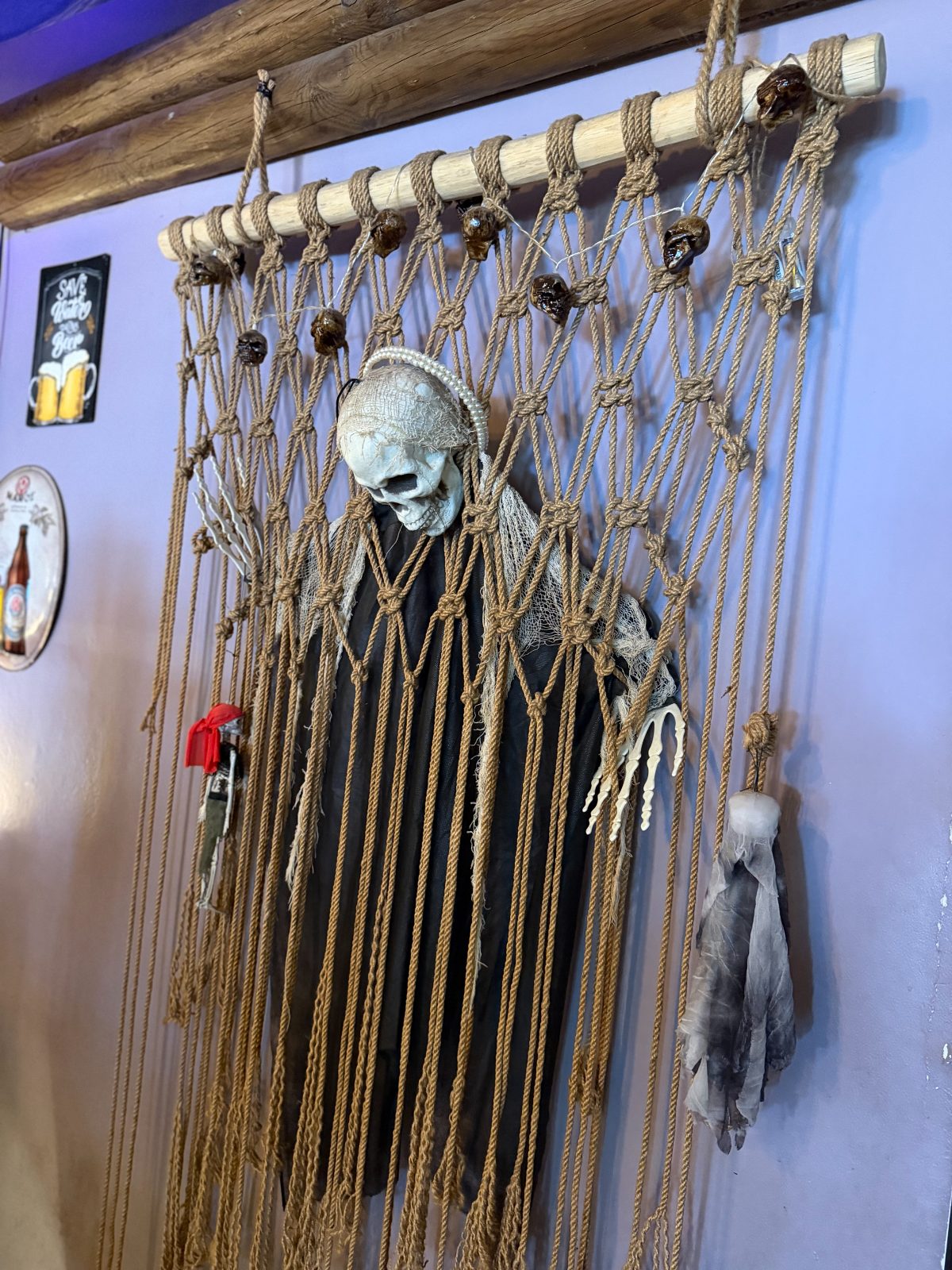 Skeletal grim reaper figure woven into a macramé wall hanging, purple light