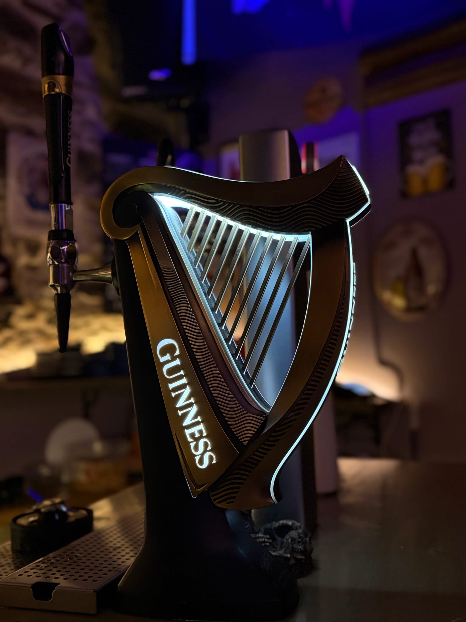 Guinness tap glowing under moody blue bar lighting